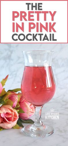 the pretty pink cocktail in a glass next to flowers on a marble countertop with text overlay