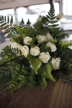 a bouquet of white roses sitting on top of a wooden table