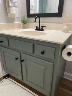 a bathroom with a sink, mirror and toilet paper