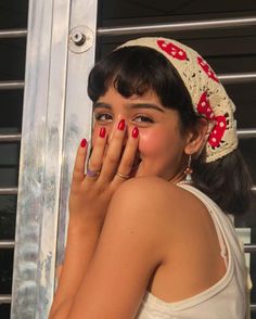 a woman with red nail polish holding her hand up to her face