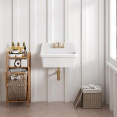 a white sink sitting next to a wooden shelf filled with bottles and toilet paper in a bathroom