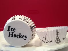 two cupcake cases sitting on top of a white plate with the words ice hockey printed on them