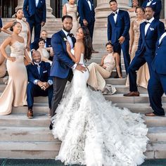 a bride and groom posing on the steps with their bridal party in the background