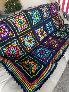 a crocheted afghan is sitting on a couch in front of a christmas tree