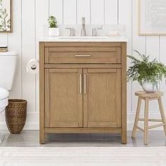 a white toilet sitting next to a wooden sink vanity in a bathroom under a mirror