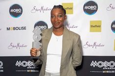 a woman standing in front of a wall holding an award