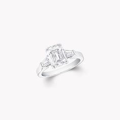 an emerald cut diamond ring with baguets on the shoulders and side stones in white gold