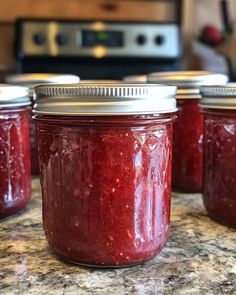 four jars filled with jam sitting on top of a counter next to a microwave oven