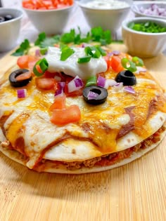 a wooden cutting board topped with pizza covered in cheese and veggie toppings