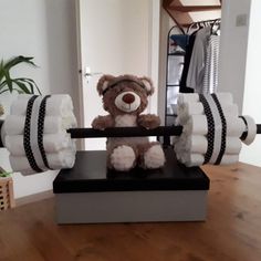 a teddy bear sitting on top of a box with rolls of toilet paper around it