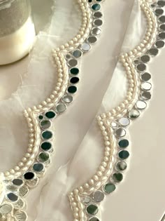 This stunning 2.5cm Elegant White Pearl And Mirror Scalloped Trim is fabulous for all your outfit edging, detailing and sew on fabric. Each intricate mirror and pearl placement are meticulously handcrafted, creating a mesmerizing border that exudes elegance and beauty. The shimmering mirror, white thread and pearls, add a touch of glamour and delicacy  to any dress.  We are constantly adding new items and you will be sure to find our complete inventory with 1000's of designs at www.lacetrimssindia.com PLEASE NOTE : ALL ORDERS ARE SHIPPED FROM THE INDIA RETURN POLICY *All broken case can be re-sent or refund if the condition is proven by photo . *Exchange item or refund case can be accepted within 5 days after receiving the item. Return shipping charge is pay by buyer if it is not our fault Mirror Design Dress, Mirror Suit Design, Mirror Work On Dupatta, Semi-stitched Dupatta With Pearl Embroidery For Wedding, White Dupatta With Pearl Embroidery, Pearl Dupatta, Elegant Lace Dupatta With Pearl Embroidery, Bollywood Style White Pearl Embroidered Fabric, Mirror Work Lace Border