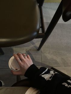 a person sitting at a table with a coffee cup in their hand and the lid off