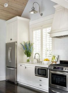 a kitchen with white cabinets and stainless steel appliances in the center, along with wood flooring