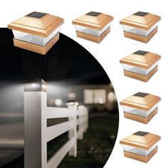 six solar powered lights on the side of a white fence at night with grass in front