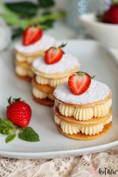 three desserts on a white plate with strawberries and powdered sugar around them