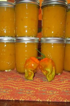 several jars filled with yellow peppers sitting on top of a table