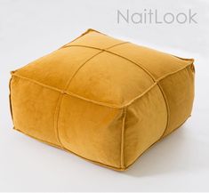 a yellow square pillow sitting on top of a white floor