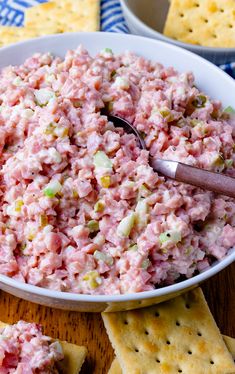 a white bowl filled with tuna salad next to crackers