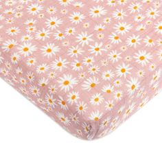 the pink and white daisy print crib sheet is folded up on top of it