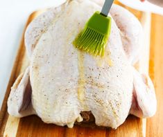 a person grating chicken with a brush on a cutting board