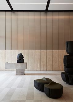 an empty room with several black and white objects on the floor in front of a wooden wall