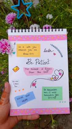 someone is holding up a notebook with the words be patient written on it in front of some flowers