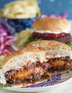 two hamburgers sitting on top of a plate next to potato chips and coleslaw