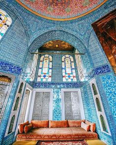 the interior of an ornate building with stained glass windows and blue tiles on the walls