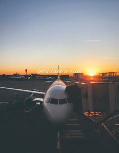 an airplane sitting on the tarmac with the sun setting in the distance behind it