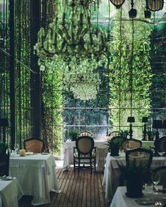 an indoor dining area with tables, chairs and chandelier hanging from the ceiling