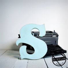 an old typewriter sitting on top of a table next to a sign with the letter s