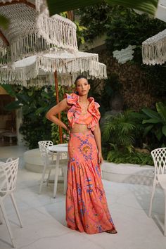 PRE-SALE DESCRIPTION: This exquisite two-piece skirt set is a statement of bold elegance, featuring a vibrant coral color adorned with intricate paisley and floral patterns in shades of blue, pink, and green. The cropped top showcases voluminous ruffled sleeves and a fitted bodice, offering a dramatic yet feminine touch. Paired with a high-waisted, tiered maxi skirt that flows effortlessly with every movement, this set is perfect for a summer getaway or a stylish day out. The lightweight fabric Pink Tiered Skirt Set For Summer, Pink Long Skirt Set For Summer, Orange Two Piece, Tiered Maxi Skirt, Summer Getaway, Ruffled Sleeves, Coral Color, Cropped Top, Fitted Bodice