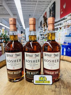 three bottles of kosher rye sitting on top of a wooden table in a store