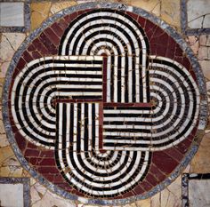 a cross made out of marble on top of a stone wall with red and white stripes