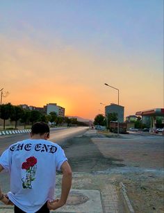 a man standing on the side of a road with his back turned to the camera