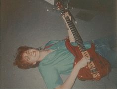 a young man laying on the floor with his guitar