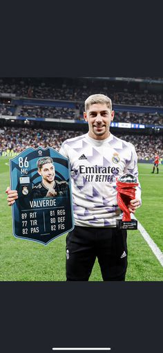 a man holding a plaque in front of him on a soccer field with the name of his team