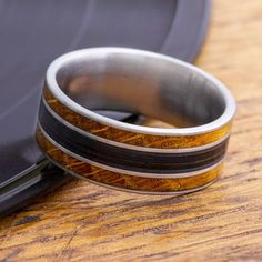 two rings sitting on top of a wooden table next to a black plate and tray