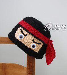 a crocheted hat with eyes and a scarf on top of a wooden chair