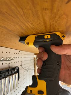 a person holding a drill in their right hand while working on a piece of wood