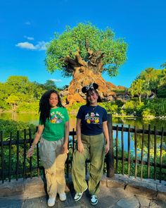 two people standing next to each other in front of the tree of life at disney's animal kingdom