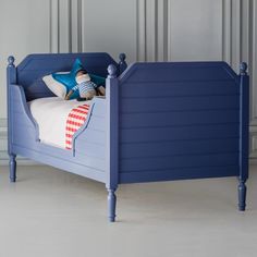 a blue bed with two pillows on top of it and a pillow in the middle