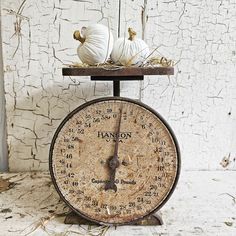 an old fashioned kitchen scale with two white pumpkins on top and hay in the middle