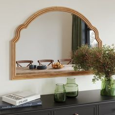 a mirror and vases on top of a black dresser in a room with white walls