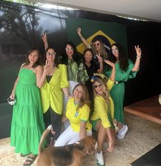 a group of women in yellow and green dresses posing for a photo with a dog