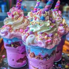 three ice cream sundaes with sprinkles and unicorn hats on top