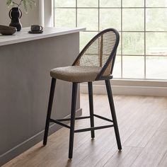 a bar stool sitting in front of a window next to a vase and potted plant