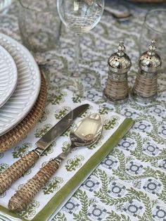 a place setting with silverware and green napkins on a tableclothed cloth