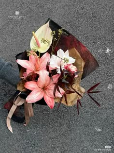 a bouquet of flowers sitting on the ground next to someone's leg and shoes