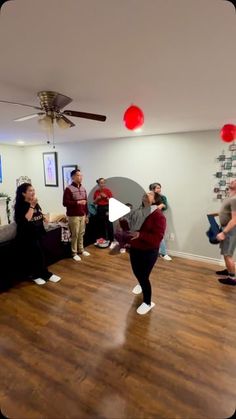 a group of people standing in a living room next to each other on top of a hard wood floor